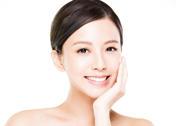 Portrait d'une femme asiatique souriante au teint éclatant sur fond blanc